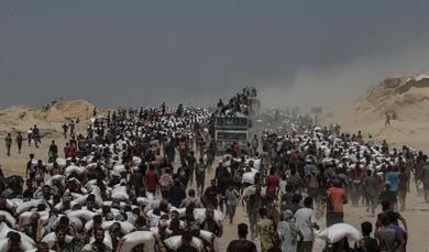 Photo: Saber Nuraldin – Displaced Palestinians carry flour from a distribution point near Zikim, northern Gaza Strip – 2025