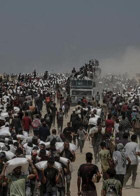 Photo: Saber Nuraldin – Displaced Palestinians carry flour from a distribution point near Zikim, northern Gaza Strip – 2025