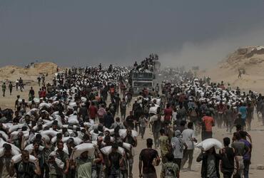 Photo: Saber Nuraldin – Displaced Palestinians carry flour from a distribution point near Zikim, northern Gaza Strip – 2025